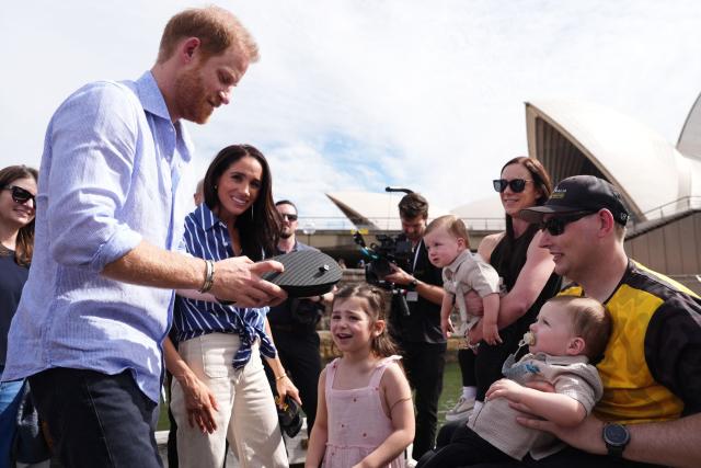 Veteran Joel Vanderzwan (R) and his family present flip-flops with the inscriptions "G'day Hazza" and "G'day Megs" to Britain's Prince Harry, Duke of Sussex, and his wife Meghan, the Duchess of Sussex, after taking part in a sailing event with members of Invictus Australia in Sydney Harbour on April 17, 2026. (Photo by Jonathan Brady / POOL / AFP)