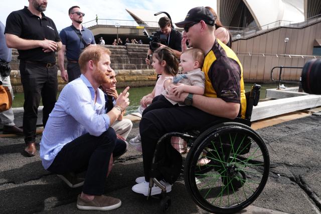 Britain's Prince Harry (L), Duke of Sussex, and his wife Meghan, the Duchess of Sussex, meet veteran Joel Vanderzwan (R) and his wife Alexandra, daughter Charlotte and twin sons Harrison and William, before taking part in a sailing event with members of Invictus Australia in Sydney Harbour on April 17, 2026. (Photo by Jonathan Brady / POOL / AFP)