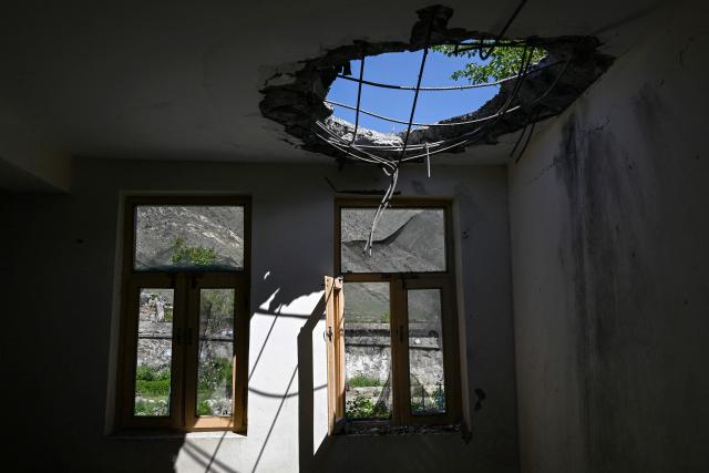 This photograph taken on April 13, 2026 shows the damaged rooftop of a school classroom after it was struck by a Pakistani mortar shell during clashes between Taliban security personnel and Pakistani forces near the Durand Line in the Barikot village of Naray district, Kunar province. There are no children in the Afghan border village of Barikot, where the school has been smashed by shells and the playground sits deserted after weeks of war with Pakistan. More than 94,000 Afghans have been displaced by the war, OCHA figures show, more than a quarter of them in Kunar province. (Photo by Wakil KOHSAR / AFP)
