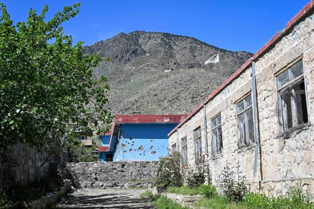 This photograph taken on April 13, 2026 shows a damaged school wall after it was struck by a Pakistani mortar shell during clashes between Taliban security personnel and Pakistani forces near the Durand Line in the Barikot village of Naray district, Kunar province. There are no children in the Afghan border village of Barikot, where the school has been smashed by shells and the playground sits deserted after weeks of war with Pakistan. More than 94,000 Afghans have been displaced by the war, OCHA figures show, more than a quarter of them in Kunar province. (Photo by Wakil KOHSAR / AFP)