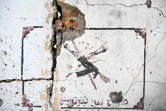 This photograph taken on April 13, 2026 shows the damaged wall of a hospital struck by Pakistani mortar shell during clashes between Taliban security personnel and Pakistani forces near the Durand Line border between Pakistan and Afghanistan in the Barikot village of Naray district, Kunar province. There are no children in the Afghan border village of Barikot, where the school has been smashed by shells and the playground sits deserted after weeks of war with Pakistan. More than 94,000 Afghans have been displaced by the war, OCHA figures show, more than a quarter of them in Kunar province. (Photo by Wakil KOHSAR / AFP)