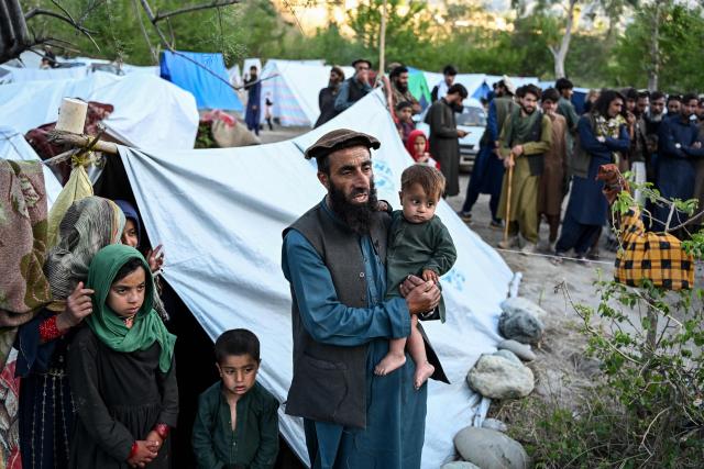 This photograph taken on April 12, 2026 shows internally displaced Afghan man Mohammad Nabi Gujar (C) speaking during an interview with AFP as he stands near temporary tents along a river amid the ongoing conflict between Pakistani forces and Taliban security personnel in the Marawara district of Kunar province. There are no children in the Afghan border village of Barikot, where the school has been smashed by shells and the playground sits deserted after weeks of war with Pakistan. More than 94,000 Afghans have been displaced by the war, OCHA figures show, more than a quarter of them in Kunar province. (Photo by Wakil KOHSAR / AFP)