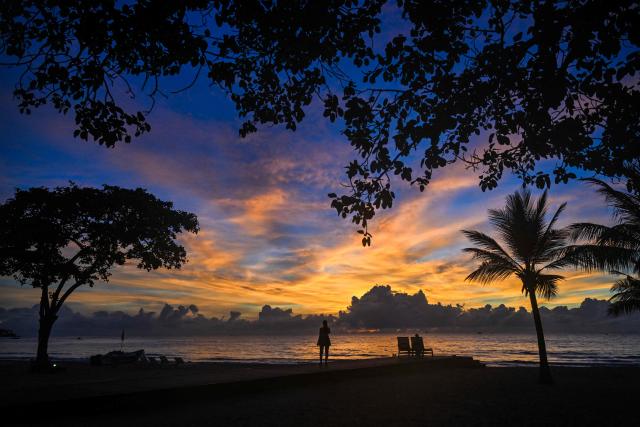 A tourist watches the sunset at a beach in Trincomalee on April 17, 2026. (Photo by Ishara S. KODIKARA / AFP)