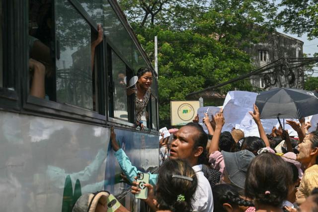 Released prisoners look out from a bus after it came out from Insein Prison, as relatives gather around it searching for their loved ones, during an amnesty to mark Myanmar's new year in Yangon on April 17, 2026. More than 4,300 prisoners were slated for release on April 17 to mark Myanmar's Thingyan new year, one of the country's many public holidays when forgiveness orders are regularly announced. (Photo by Sai Aung MAIN / AFP)