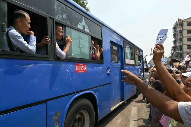 Released prisoners look out from a bus after it came out from Insein Prison, as relatives gather around it searching for their loved ones, during an amnesty to mark Myanmar's new year in Yangon on April 17, 2026. More than 4,300 prisoners were slated for release on April 17 to mark Myanmar's Thingyan new year, one of the country's many public holidays when forgiveness orders are regularly announced. (Photo by Sai Aung MAIN / AFP)