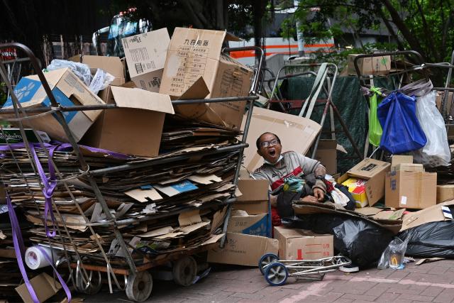 A card board collector takes a rest on a street in Hong Kong on April 17, 2026. (Photo by Peter PARKS / AFP)