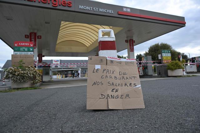 A placard reading "The price of fuel: Our salaries at risk" is pictured near a gas station blocked by Argedis employees to demand fuel assistance in Saint-Aubin-de-Terregatte, western France on April 17, 2026. The CGT union at Argedis, a TotalEnergies subsidiary that operates around 200 service stations, notably on motorways, has called on employees to strike on April 17, 2026 to demand financial assistance with fuel costs, amid soaring prices, the union said on April 16. (Photo by Damien MEYER / AFP)