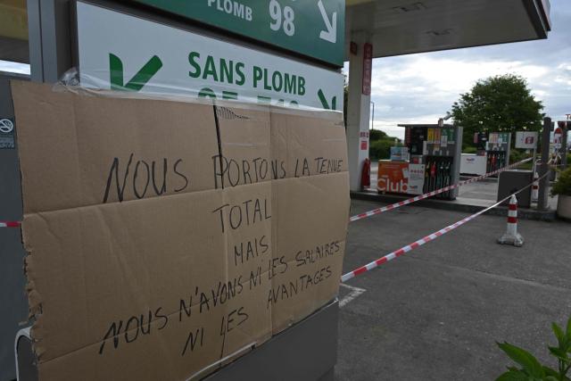 A placard reading "We wear Total's uniform but get neither the salaries nor the benefits" is pictured at a gas station blocked by Argedis employees to demand fuel assistance in Saint-Aubin-de-Terregatte, western France on April 17, 2026. The CGT union at Argedis, a TotalEnergies subsidiary that operates around 200 service stations, notably on motorways, has called on employees to strike on April 17, 2026 to demand financial assistance with fuel costs, amid soaring prices, the union said on April 16. (Photo by Damien MEYER / AFP)