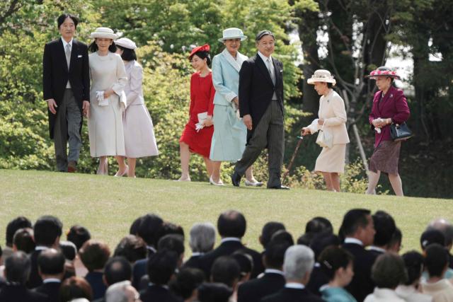 Japan's Emperor Naruhito (Center, R) and Empress Masako (Center, L) with other royal family members walk down a hill to greet guests during the spring garden party at the Akasaka Palace's imperial garden in Tokyo on April 17, 2026. (Photo by Kazuhiro NOGI / POOL / AFP)