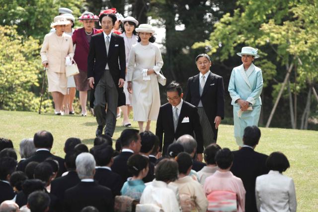 Japan's Emperor Naruhito (2nd R) and Empress Masako (R) with other royal family members walk down a hill to greet guests during the spring garden party at the Akasaka Palace's imperial garden in Tokyo on April 17, 2026. (Photo by Kazuhiro NOGI / POOL / AFP)