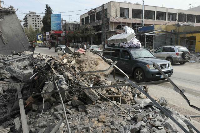 Displaced residents drive past a destroyed building as they return back to the southern Lebanese city of Nabatieh on April 17, 2026. A 10-day ceasefire deal struck between Lebanon and Israel took effect on April 17, sending displaced residents streaming south towards their homes, even as the Lebanese army warned of "a number of violations" in the area. (Photo by MAHMOUD ZAYYAT / AFP)