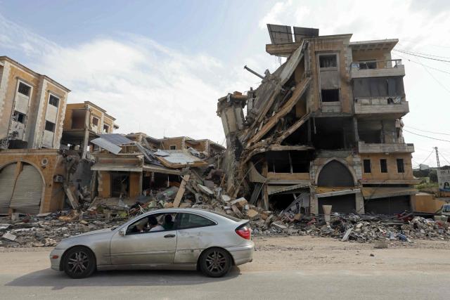 Displaced residents drive past a destroyed building as they return back to the southern Lebanese city of Nabatieh on April 17, 2026. A 10-day ceasefire deal struck between Lebanon and Israel took effect on April 17, sending displaced residents streaming south towards their homes, even as the Lebanese army warned of "a number of violations" in the area. (Photo by MAHMOUD ZAYYAT / AFP)