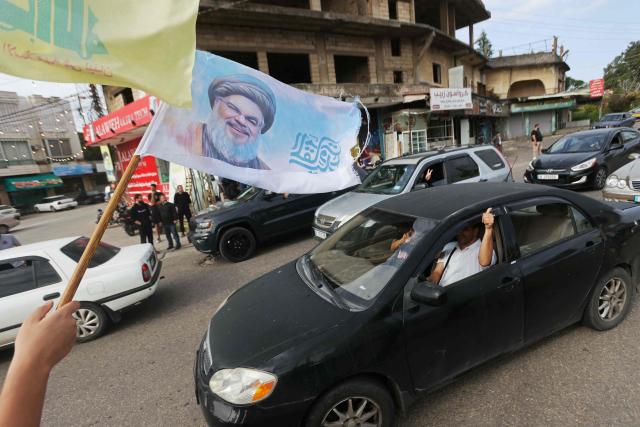 A man waves a flag with a portrait of slain Hezbollah leader Hassan Nasrallah while celebrating the ceasefire, in the southern Lebanese town of Marwanieh on April 17, 2026. A 10-day ceasefire deal struck between Lebanon and Israel took effect on April 17, sending displaced residents streaming south towards their homes, even as the Lebanese army warned of "a number of violations" in the area. (Photo by MAHMOUD ZAYYAT / AFP)