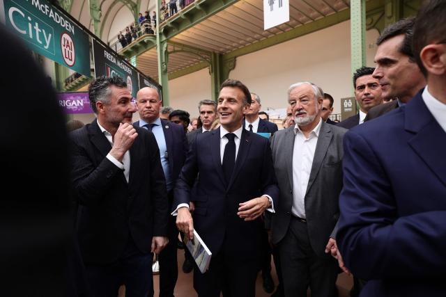 French President Emmanuel Macron (C) visits the Paris Book Fair at the Grand Palais in Paris on April 17, 2026. The fair, which runs until April 19, spotlights comic books as its central theme. (Photo by Teresa SUAREZ / POOL / AFP)