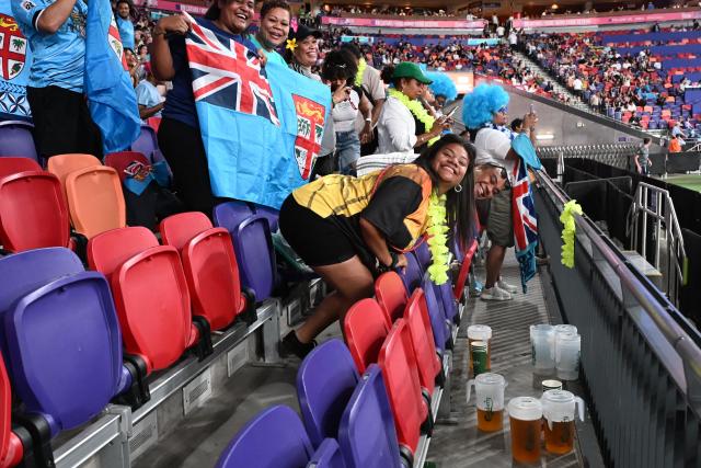 Fiji fans cheer their team on the first day of the 2026 Rugby Sevens Hong Kong tournament at the Kai Tak sports stadium on April 17, 2026. The first Hong Kong Sevens took place in front of a few thousand curious spectators and some of the players wore gym shoes in the mud instead of rugby boots. Fast forward 50 years and the event has grown into a sold-out three-day festival of global repute mixing sport with socialising, schmoozing and big business. (Photo by Peter PARKS / AFP)