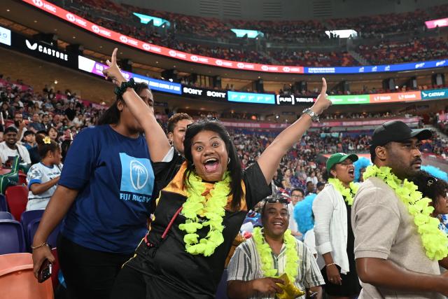 Fiji fans cheer their team on the first day of the 2026 Rugby Sevens Hong Kong tournament at the Kai Tak sports stadium on April 17, 2026. The first Hong Kong Sevens took place in front of a few thousand curious spectators and some of the players wore gym shoes in the mud instead of rugby boots. Fast forward 50 years and the event has grown into a sold-out three-day festival of global repute mixing sport with socialising, schmoozing and big business. (Photo by Peter PARKS / AFP)