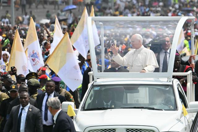 Pope Leo XIV (2nd R) waves to the crowd from the Popemobile as he arrives to lead the Holy Mass at the area in front of Japoma Stadium in Douala on the fifth day of an 11-day apostolic journey to Africa, on April 17, 2026. (Photo by Alberto PIZZOLI / AFP)