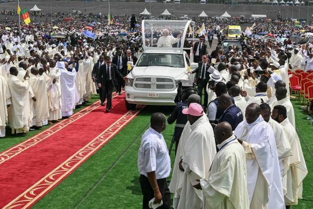 Pope Leo XIV (C) waves to the crowd from the Popemobile as he arrives to lead the Holy Mass at the area in front of Japoma Stadium in Douala on the fifth day of an 11-day apostolic journey to Africa, on April 17, 2026. (Photo by Alberto PIZZOLI / AFP)