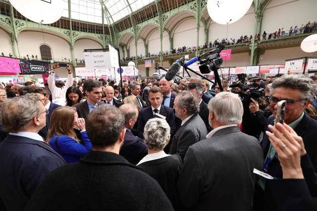 French President Emmanuel Macron (C) visits the Paris Book Fair at the Grand Palais in Paris on April 17, 2026. The fair, which runs until April 19, spotlights comic books as its central theme. (Photo by Teresa SUAREZ / POOL / AFP)
