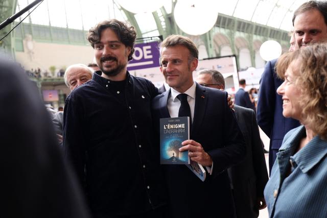 French President Emmanuel Macron (C) visits the Paris Book Fair at the Grand Palais in Paris on April 17, 2026. The fair, which runs until April 19, spotlights comic books as its central theme. (Photo by Teresa SUAREZ / POOL / AFP)