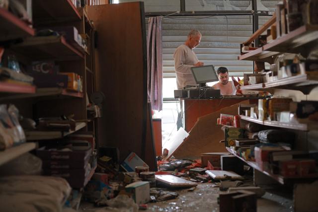 Men inspect destruction in their shop upon his return to the southern Lebanese city of Nabatieh on April 17, 2026. Thousands of displaced Lebanese civilians took to the road on April 17, hoping that a 10-day ceasefire with Israel would allow them to return to their homes in southern Beirut and the country's war-torn south. (Photo by ibrahim AMRO / AFP)