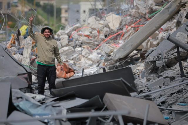 A man flashes the victory sign as he inspects destruction upon his return to the southern Lebanese city of Nabatieh on April 17, 2026. Thousands of displaced Lebanese civilians took to the road on April 17, hoping that a 10-day ceasefire with Israel would allow them to return to their homes in southern Beirut and the country's war-torn south. (Photo by ibrahim AMRO / AFP)