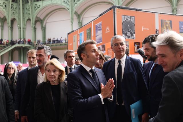 French President Emmanuel Macron (C) and France's Culture Minister Catherine Pegard (front L) visit Paris Book Fair at the Grand Palais in Paris on April 17, 2026. The fair, which runs until April 19, spotlights comic books as its central theme. (Photo by Teresa SUAREZ / POOL / AFP)