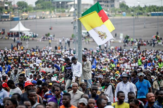 TOPSHOT - Faithfuls pray surrounding a pole with the Vatican and Cameroonian flags as Pope Leo XIV leads the Holy Mass at the area in front of Japoma Stadium in Douala on the fifth day of an 11-day apostolic journey to Africa, on April 17, 2026. (Photo by Patrick MEINHARDT / AFP)