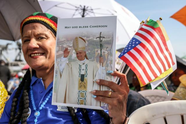 A faithful holds a booklet commemorating the visit of Pope Leo XIV to Cameroon as he leads the Holy Mass at the area in front of Japoma Stadium in Douala on the fifth day of an 11-day apostolic journey to Africa, on April 17, 2026. (Photo by Daniel Beloumou Olomo / AFP)
