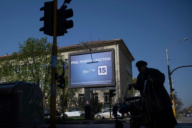 Pedestrians walk past an electoral billboard of the GERB party in Sofia on April 17, 2026. Bulgaria will hold its eighth general election in five years on April 19, 2026, with ex-president Rumen Radev's new grouping tipped to win a ballot many hope will end chronic instability. (Photo by Nikolay DOYCHINOV / AFP)