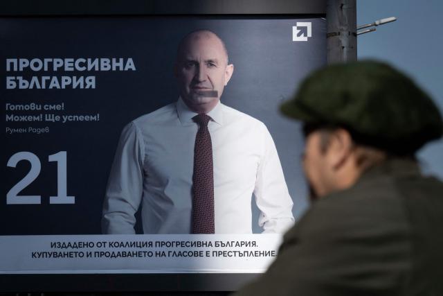 Pedestrians walk past an electoral billboard of the Progressive Bulgaria coalition's leader and former President Rumen Radev in Sofia on April 17, 2026. Bulgaria will hold its eighth general election in five years on April 19, 2026, with ex-president Rumen Radev's new grouping tipped to win a ballot many hope will end chronic instability. (Photo by Nikolay DOYCHINOV / AFP)