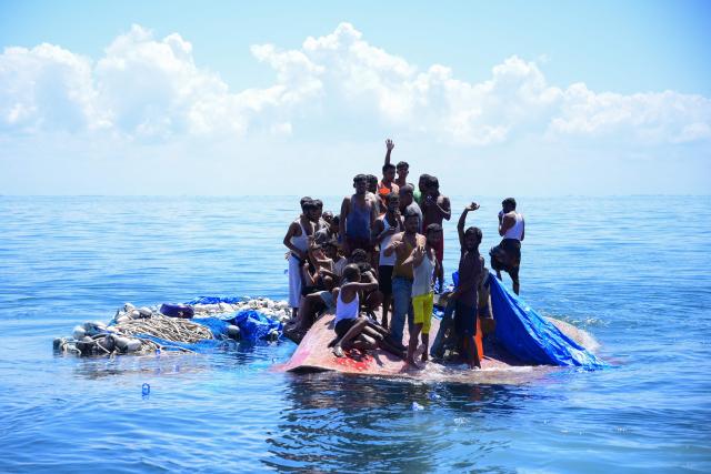 (FILES) Rohingya refugees wait to be rescued from the hull of their capsized boat as a National Search and Rescue Agency (BASARNAS) vessel approaches in waters some 16 nautical miles (29 kilometers) off west Aceh on March 21, 2024. Last year was the deadliest on record for Rohingya refugees fleeing by sea, with nearly 900 reported dead or missing in shipwrecks in the region, the United Nations said on April 17, 2026. (Photo by Zahlul AKBAR / AFP)
