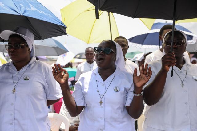 Faithfuls gesture as Pope Leo XIV leads the Holy Mass at the area in front of Japoma Stadium in Douala on the fifth day of an 11-day apostolic journey to Africa, on April 17, 2026. (Photo by Daniel Beloumou Olomo / AFP)