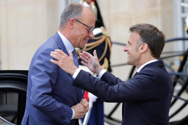 France's President Emmanuel Macron (R) welcomes German chancellor Friedrich Merz ahead of a meeting of allies to consider sending a multinational force to ensure security and free-flowing trade in the Strait of Hormuz, at the presidential Elysee Palace in Paris on April 17, 2026. French President Emmanuel Macron and UK Prime Minister Keir Starmer chair a meeting of allies to consider sending a multinational force to ensure security and free-flowing trade in the Strait of Hormuz once the current conflict between Iran and the US and Israel ends. Iran imposed the blockade on the critical shipping bottleneck as soon as the US and Israel launched the war against the Islamic republic on February 28, leading to a surge in global energy prices. Even with a shaky ceasefire in place, the US is now imposing its own blockade on Iranian ports. (Photo by Ludovic MARIN / AFP)