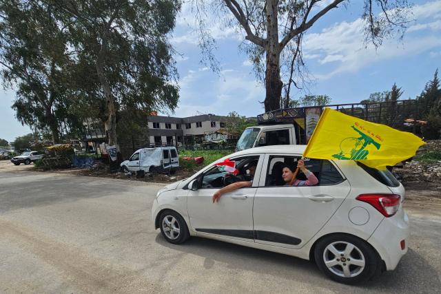 A displaced resident carries a flag of Hezbollah while driving back to his home in the southern Lebanese city of Nabatieh on April 17, 2026. Thousands of displaced Lebanese civilians took to the road on April 17, hoping that a 10-day ceasefire with Israel would allow them to return to their homes in southern Beirut and the country's war-torn south. (Photo by AFP)