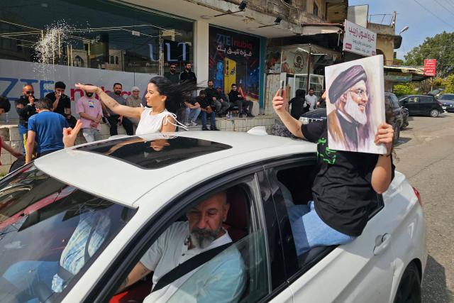 A displaced resident holds a portrait of slain Hezbollah leader Hassan Nasrallah while driving back to his home in the southern Lebanese area of Zefta on April 17, 2026. Thousands of displaced Lebanese civilians took to the road on April 17, hoping that a 10-day ceasefire with Israel would allow them to return to their homes in southern Beirut and the country's war-torn south. (Photo by AFP)