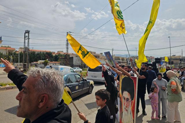 People wave flags of Hezbollah as displaced residents drive back to their homes in the southern Lebanese area of Habbouch on April 17, 2026. Thousands of displaced Lebanese civilians took to the road on April 17, hoping that a 10-day ceasefire with Israel would allow them to return to their homes in southern Beirut and the country's war-torn south. (Photo by AFP)