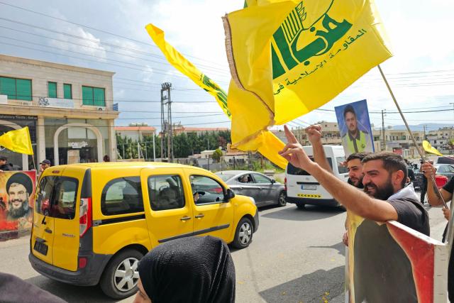 People wave flags of Hezbollah as displaced residents drive back to their homes in the southern Lebanese area of Habbouch on April 17, 2026. Thousands of displaced Lebanese civilians took to the road on April 17, hoping that a 10-day ceasefire with Israel would allow them to return to their homes in southern Beirut and the country's war-torn south. (Photo by AFP)