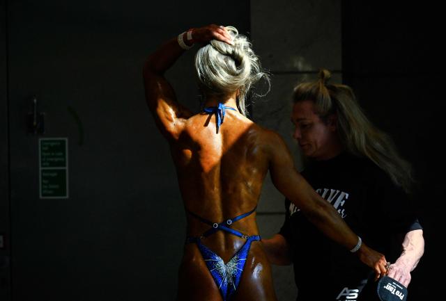 A woman prepares for a bodybuilding contest at the FIBO trade show for health, fitness and wellness in Cologne, western Germany on April 17, 2026. (Photo by Ina FASSBENDER / AFP)
