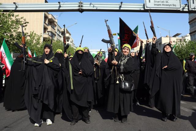 TOPSHOT - Iranian women brandish their rifles as they take part in a rally dubbed “Sacrificed Girls” to pay tribute to women killed during the Middle East war in Tehran on April 17, 2026. On February 28, Israel and the United States launched strikes on Iran killing its supreme leader and triggering a war that spread across the Middle East and unleashed chaos across global markets and sent oil prices soaring. (Photo by AFP) / 
