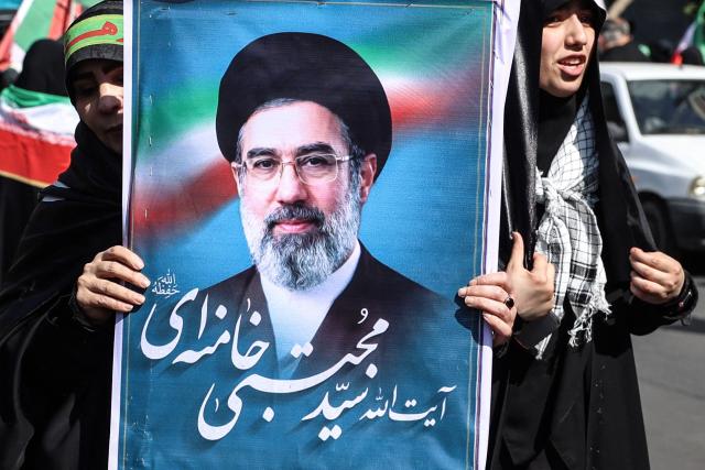 An Iranian woman holds up an image of Iran’s new supreme leader Ayatollah Mojtaba Khamenei as she takes part in a rally dubbed “Sacrificed Girls” to pay tribute to women killed during the Middle East war, in Tehran on April 17, 2026. On February 28, Israel and the United States launched strikes on Iran killing its supreme leader and triggering a war that spread across the Middle East and unleashed chaos across global markets and sent oil prices soaring. (Photo by AFP) / 