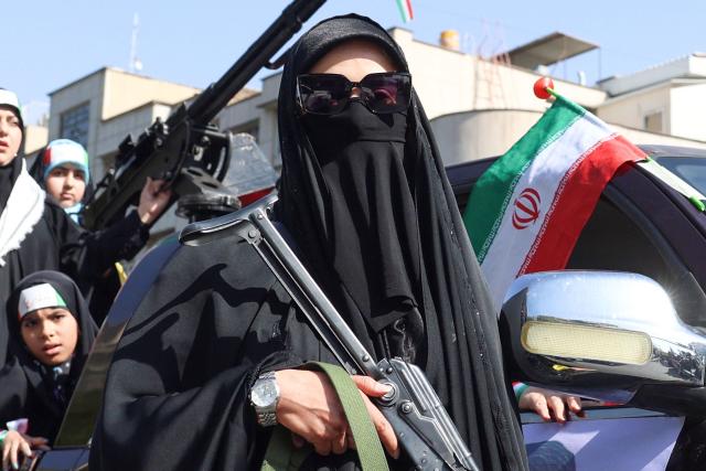 An Iranian woman brandishes a rifle during a rally dubbed “Sacrificed Girls” to pay tribute to women killed during the Middle East war in Tehran on April 17, 2026. On February 28, Israel and the United States launched strikes on Iran killing its supreme leader and triggering a war that spread across the Middle East and unleashed chaos across global markets and sent oil prices soaring. (Photo by AFP) / 