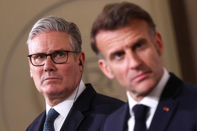 Britain's Prime Minister Keir Starmer (L) reacts behind France's President Emmanuel Macron as he attends a joint press conference following an international summit on efforts to reopen the Strait of Hormuz at the Elysee Presidential Palace in Paris on April 17, 2026. French President Emmanuel Macron and UK Prime Minister Keir Starmer chair a meeting of allies to consider sending a multinational force to ensure security and free-flowing trade in the Strait of Hormuz once the current conflict between Iran and the US and Israel ends. Iran imposed the blockade on the critical shipping bottleneck as soon as the US and Israel launched the war against the Islamic republic on February 28, leading to a surge in global energy prices. Even with a shaky ceasefire in place, the US is now imposing its own blockade on Iranian ports. (Photo by Tom Nicholson / POOL / AFP)