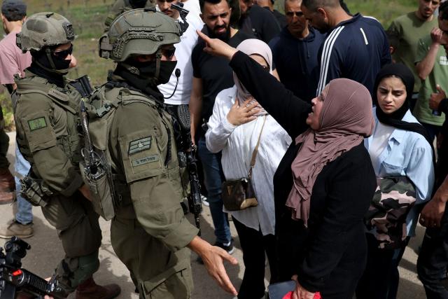 A Palestinian woman reacts towards Israeli security forces as they forcibly remove Palestinians trying to reach their land after Israeli settlers reportedly attacked local farmers working on their land, spraying them with pepper spray, near the Palestinian village of Halhoul, south of the Israel-occupied West Bank city of Hebron, on April 17, 2026. Violence in the Palestinian West Bank, which Israel has occupied since 1967, has soared since the Hamas attack on Israel triggered the Gaza war in October 2023. (Photo by HAZEM BADER / AFP)
