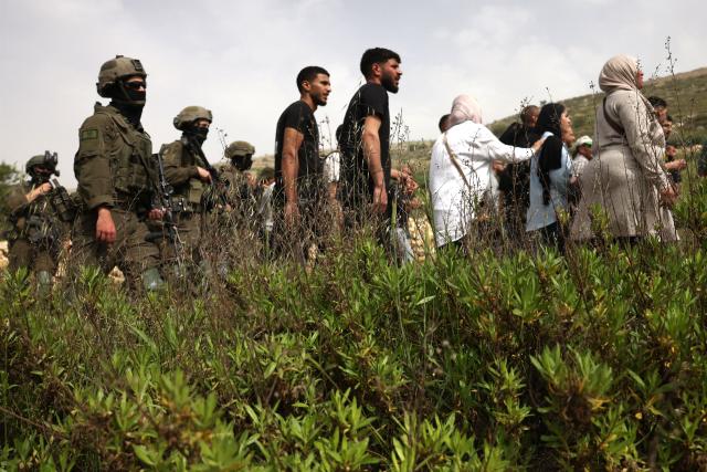 Israeli security forces (L)  direct Palestinians as they forcibly remove them from trying to reach their land after Israeli settlers reportedly attacked local farmers working on their land, spraying them with pepper spray, near the Palestinian village of Halhoul, south of the Israel-occupied West Bank city of Hebron, on April 17, 2026. (Photo by HAZEM BADER / AFP)