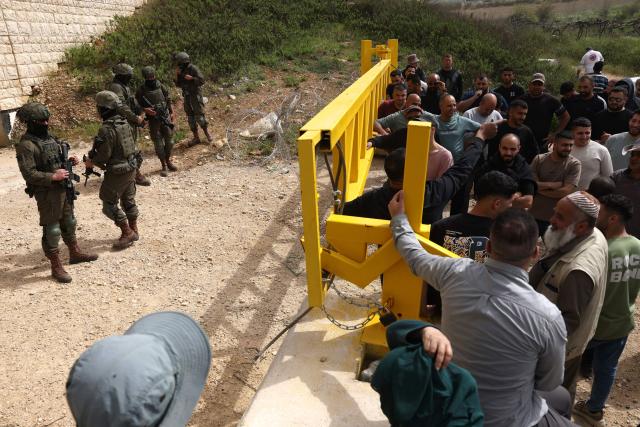 Israeli security forces drop a barrier as they forcibly remove Palestinians from trying to reach their land after Israeli settlers reportedly attacked local farmers working on their land, spraying them with pepper spray, near the Palestinian village of Halhoul, south of the Israel-occupied West Bank city of Hebron, on April 17, 2026. (Photo by HAZEM BADER / AFP)