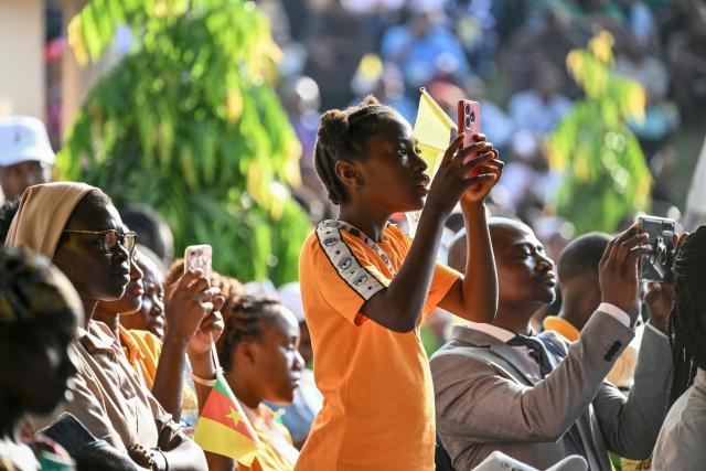 A child takes a photo while people meet with Pope Leo XIV at the Catholic University of Central Africa in Yaounde on the fifth day of an 11-day apostolic journey to Africa, on April 17, 2026. (Photo by Alberto PIZZOLI / AFP)