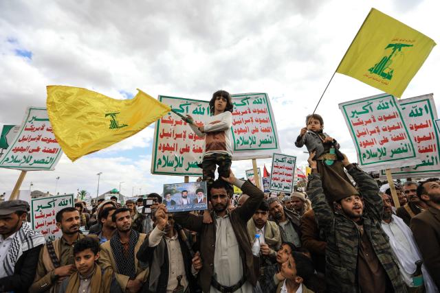 Two young boys standing on the shoulders of supporters of the Iran-backed Houthi movement as they wave the Lebanese Hezbollah party flag, as they rally in solidarity with Iran and Lebanon in the Yemeni capital Sanaa on April 17, 2026. The Middle East war has created an "unprecedented shock" for the region's economies with no guarantee of a quick recovery, a senior International Monetary Fund official has told AFP. Five of the Gulf's eight oil- and gas-producing countries face a contraction this year, the IMF said in a regional report published on April 16. (Photo by Mohammed HUWAIS / AFP)
