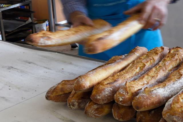 (FILES) A baker removes bread from an oven during the 20th edition of the bread day (Fete du pain) on May 8, 2015 in Paris. Employees at independent bakeries and florists who wish to do so will be able to work on May 1, 2026, Labour Day, France's prime minister  announced on April 17, 2026, after rejecting a bill that would have allowed work to be extended on this public holiday. (Photo by LOIC VENANCE / AFP)