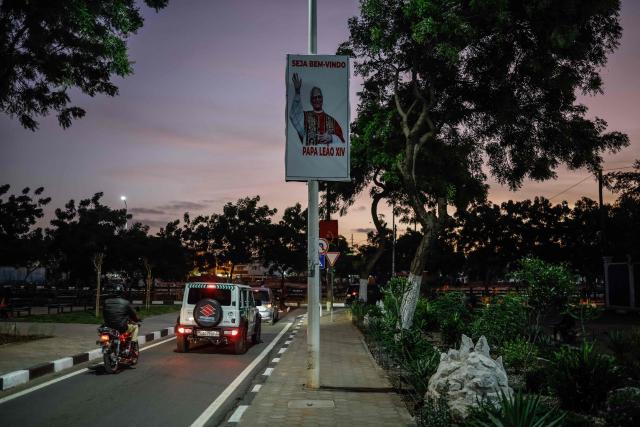 Motorists drive past to a poster welcoming Pope Leo XIV ahead of his visit to Angola as part of an 11-day apostolic journey to Africa, in Luanda, on April 17, 2026. (Photo by Phill Magakoe / AFP)